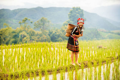 Full length of woman standing on rice paddy