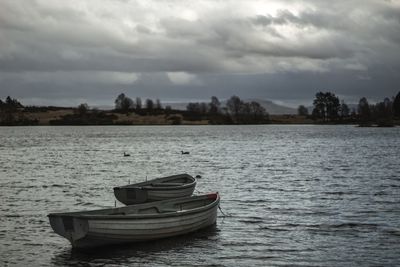 Boat moored in lake against sky