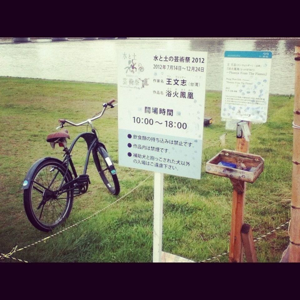 bicycle, transportation, text, mode of transport, land vehicle, western script, communication, parked, parking, stationary, grass, field, sign, motorcycle, day, outdoors, information sign, auto post production filter, no people, warning sign