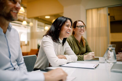 Cheerful colleagues having sales meeting at conference table in office