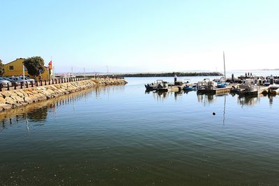 Boats moored in harbor against clear sky