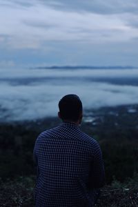 Rear view of man looking at sea against sky