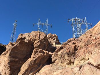 Low angle view of electricity pylon against clear blue sky