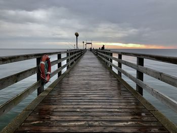 Pier on footbridge over sea against sky