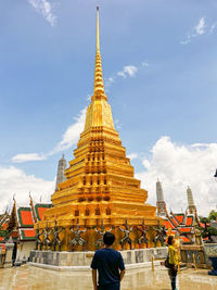 People outside temple against sky