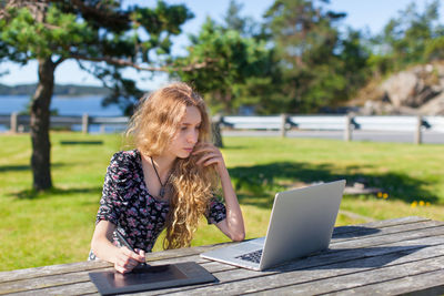 Young woman using laptop while sitting on table
