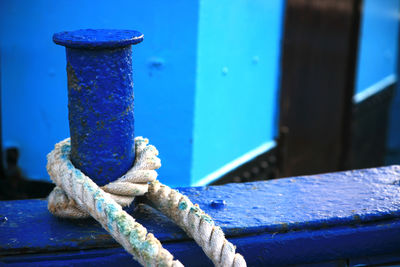 Close-up of rope tied on metal against blue wall