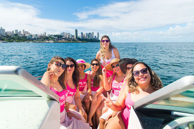 Women in bikini sitting on a boat wearing pink outfit. 