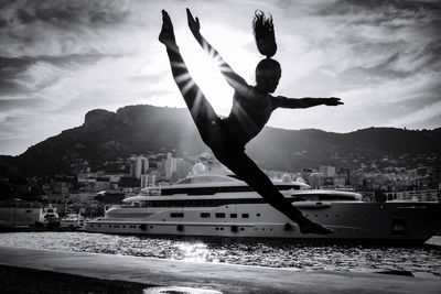 Man jumping in city against sky