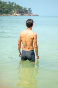 Shirtless mature man standing in sea