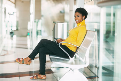 Side view of smiling young woman sitting on chair