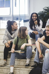 Smiling multi-ethnic high school students sitting on steps