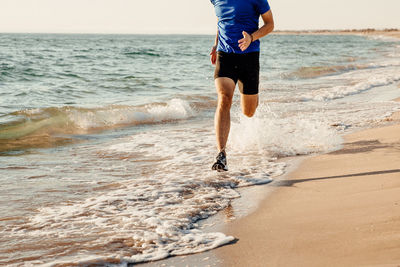 Low section of man running on beach