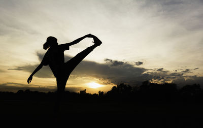 Silhouette man standing on field against sky during sunset