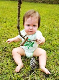 Portrait of cute baby holding stick on grassy field