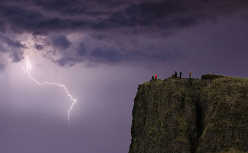 Low angle view of lightning over rocks against sky