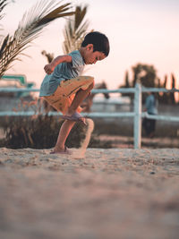 Asian kid paly sand at horse ranch while sunset.dramatic low key of simple life style of childhood.