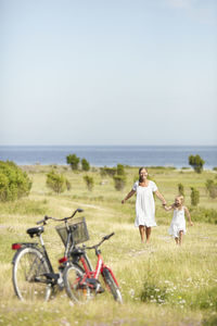 Mother with daughter walking on meadow