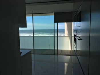 Swimming pool by sea against sky seen through window