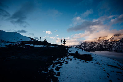People standing on snowcapped mountain against sky