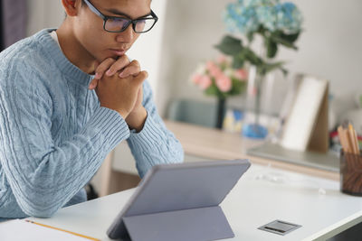 Midsection of man using mobile phone while sitting on table