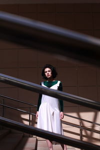 Portrait of woman standing against railing