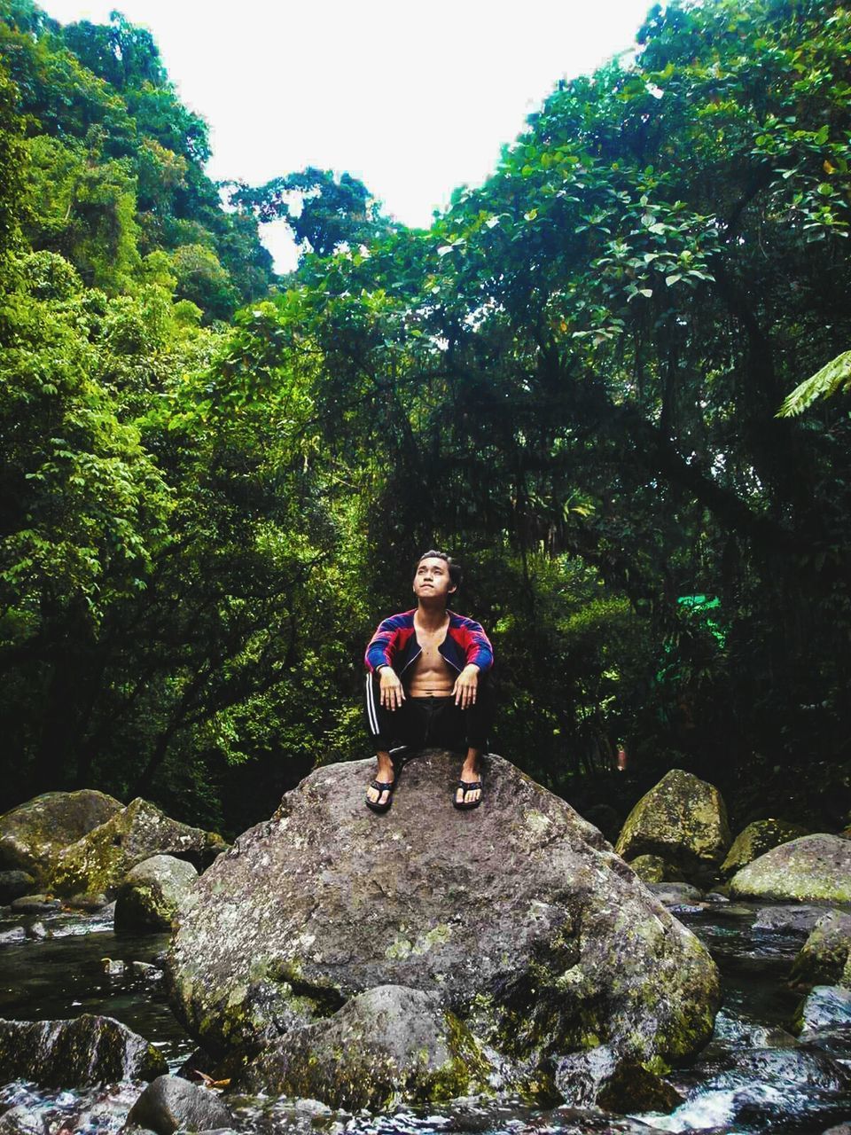FULL LENGTH OF WOMAN SITTING ON ROCK IN FOREST
