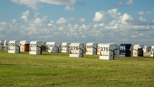 Hooded beach chairs on field against sky