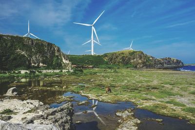 Wind turbines on rocks against blue sky