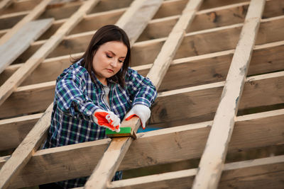 Low angle view of woman working in wooden plank