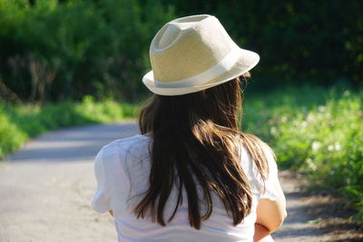 Rear view of woman wearing hat while sitting on road