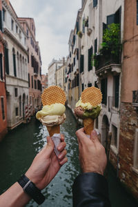 Midsection of person holding ice cream cone in canal