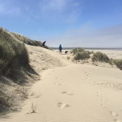 Boys with dog enjoying at beach against sky