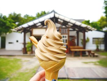 Cropped image of woman holding ice cream against sky