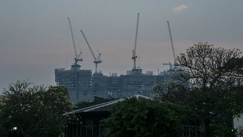 Cranes and buildings against sky