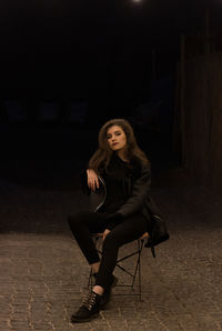 Portrait of beautiful woman sitting against illuminated lights