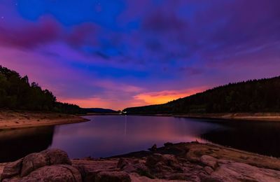 Scenic view of river against sky at sunset