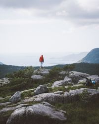 Rear view of man standing on mountain against sky