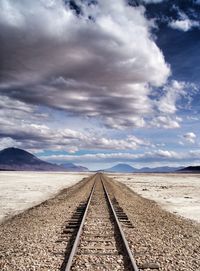 Railroad tracks in desert against sky