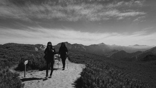 People walking on mountain against sky