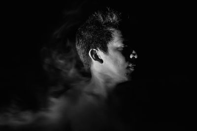 Close-up portrait of shirtless man against black background