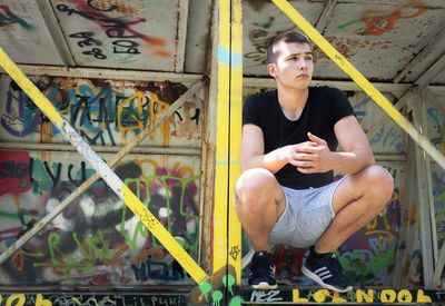 Full length of young man sitting on wall