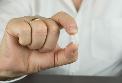 Cropped hand of businessman holding medicine at desk in office