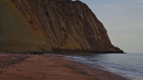 Rock formation on beach against sky