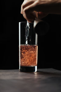 Cropped hand of man holding glass on table