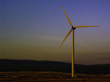 Windmill on field against sky during sunset