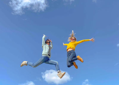 Low angle view of woman jumping against sky