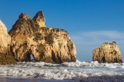 Rock formation on beach against clear sky