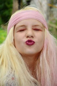 Close-up of girl wearing wig puckering lips while sitting outdoors