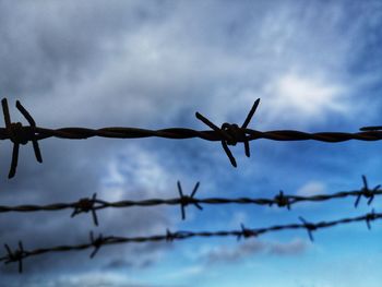 Low angle view of barbed wire against sky